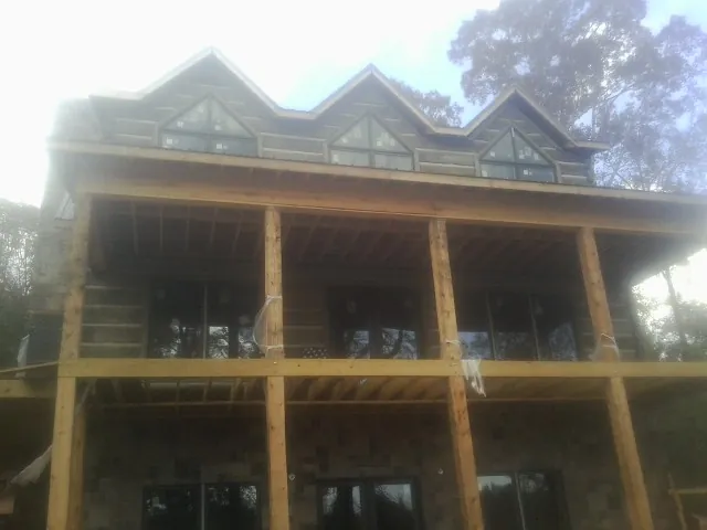 Dormers and porch framing on a large log home under construction — Roof Coating work by our crew in North Norwich