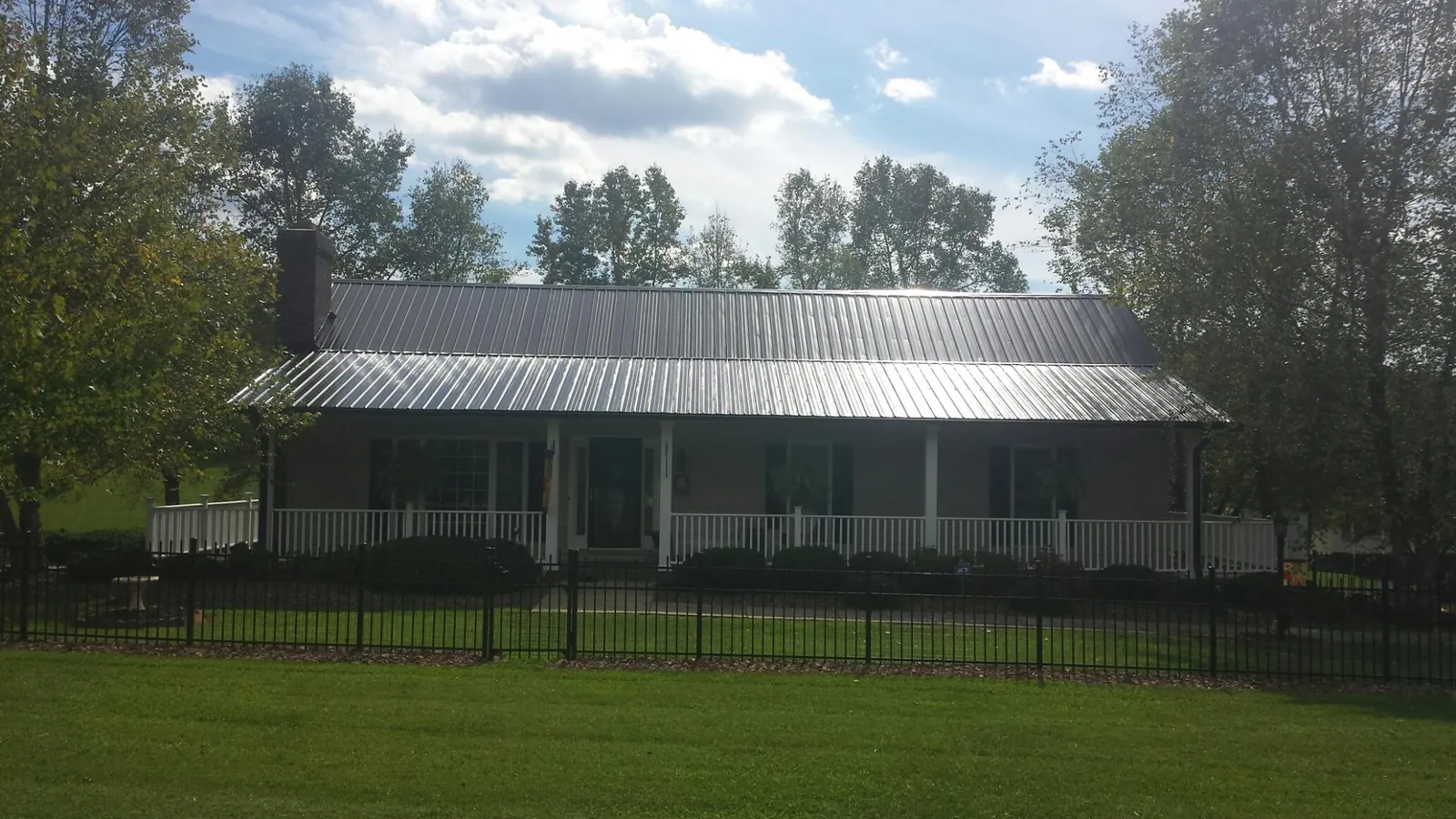 Gray metal roof on a brick ranch with a full width front porch — Gutter Guard Installation work by our crew in North Norwich
