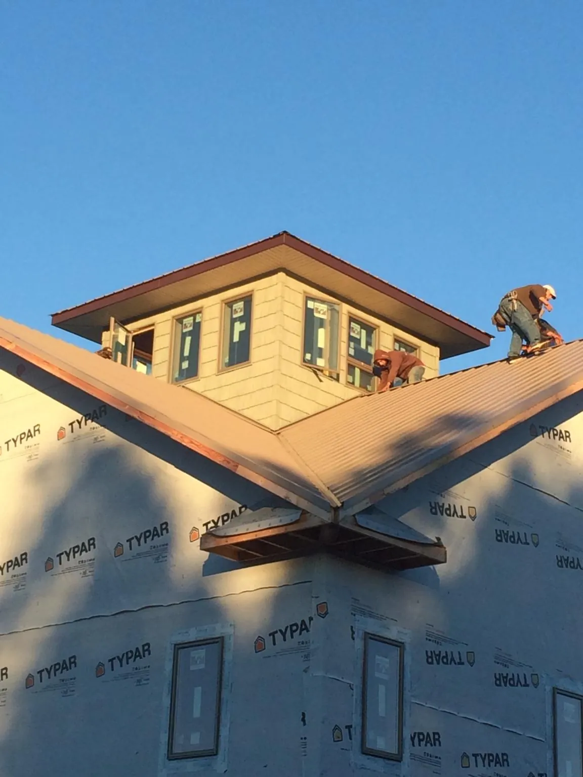 Roofers working around a rooftop cupola on a new metal roof at sunset — Roof Waterproofing in North Norwich by Roofing Brothers